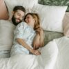 Couple enlacé le matin dans un lit – illustration des bienfaits des câlins matinaux sur le stress et la complicité.